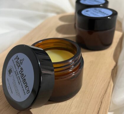 צנצנת זכוכית כהה עם מכסה פתוח ומשחה צהובה